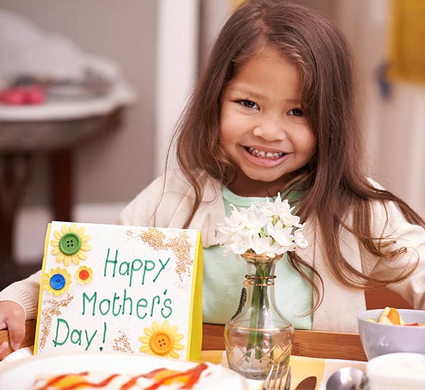 Young girl carrying a tray to her mum for breakfast in bed on Mother’s Day