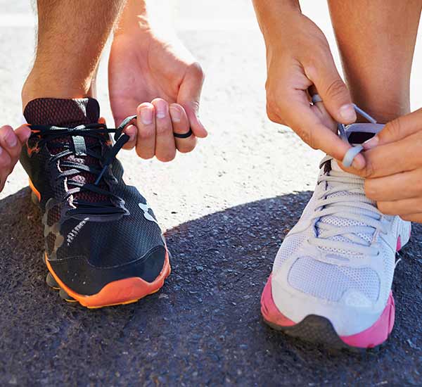 man and woman lacing up their running shoes