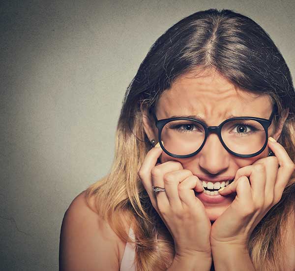 Girl with glasses biting her finger nails