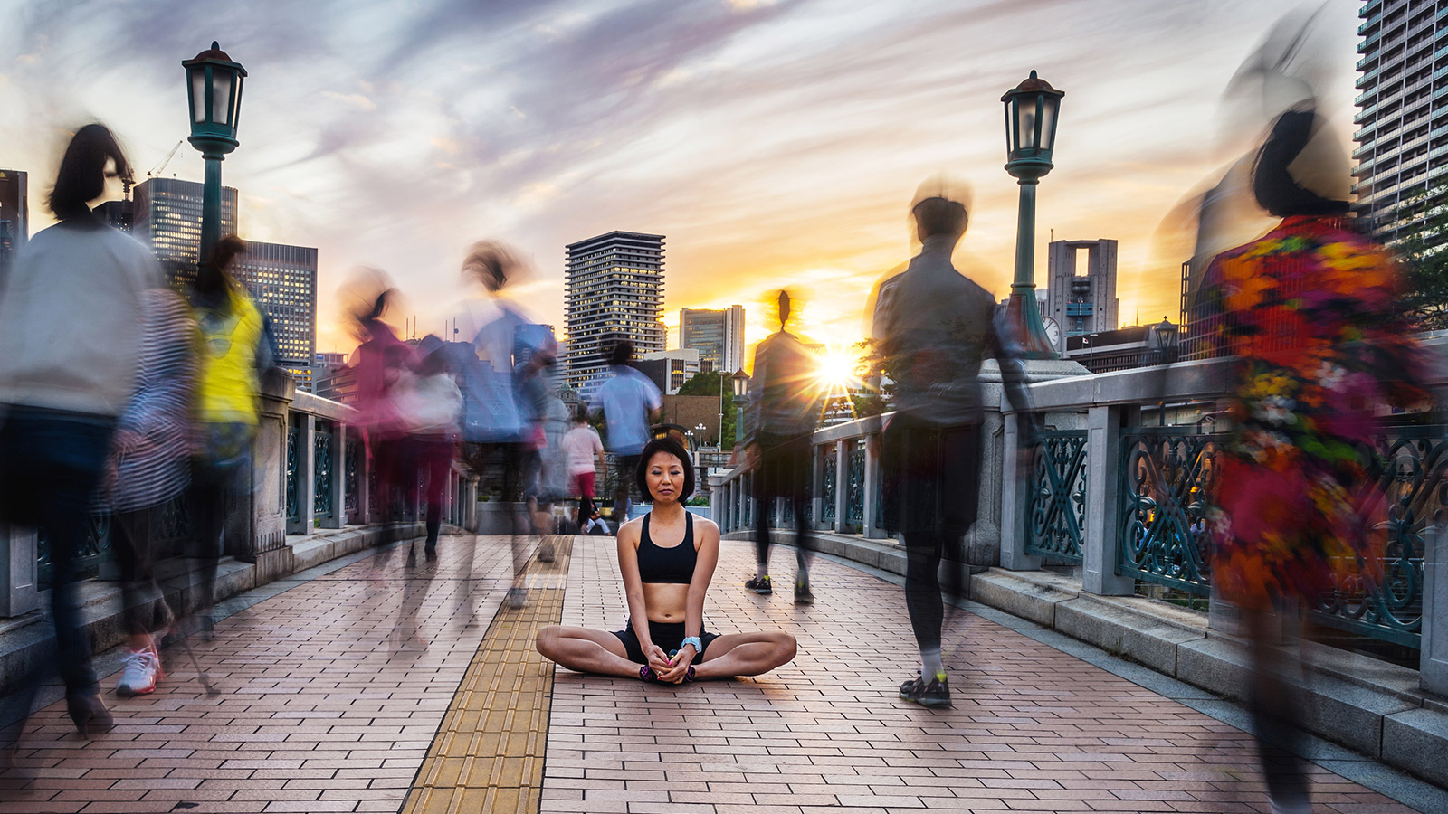 Image on woman meditating on a blurry busy bridge