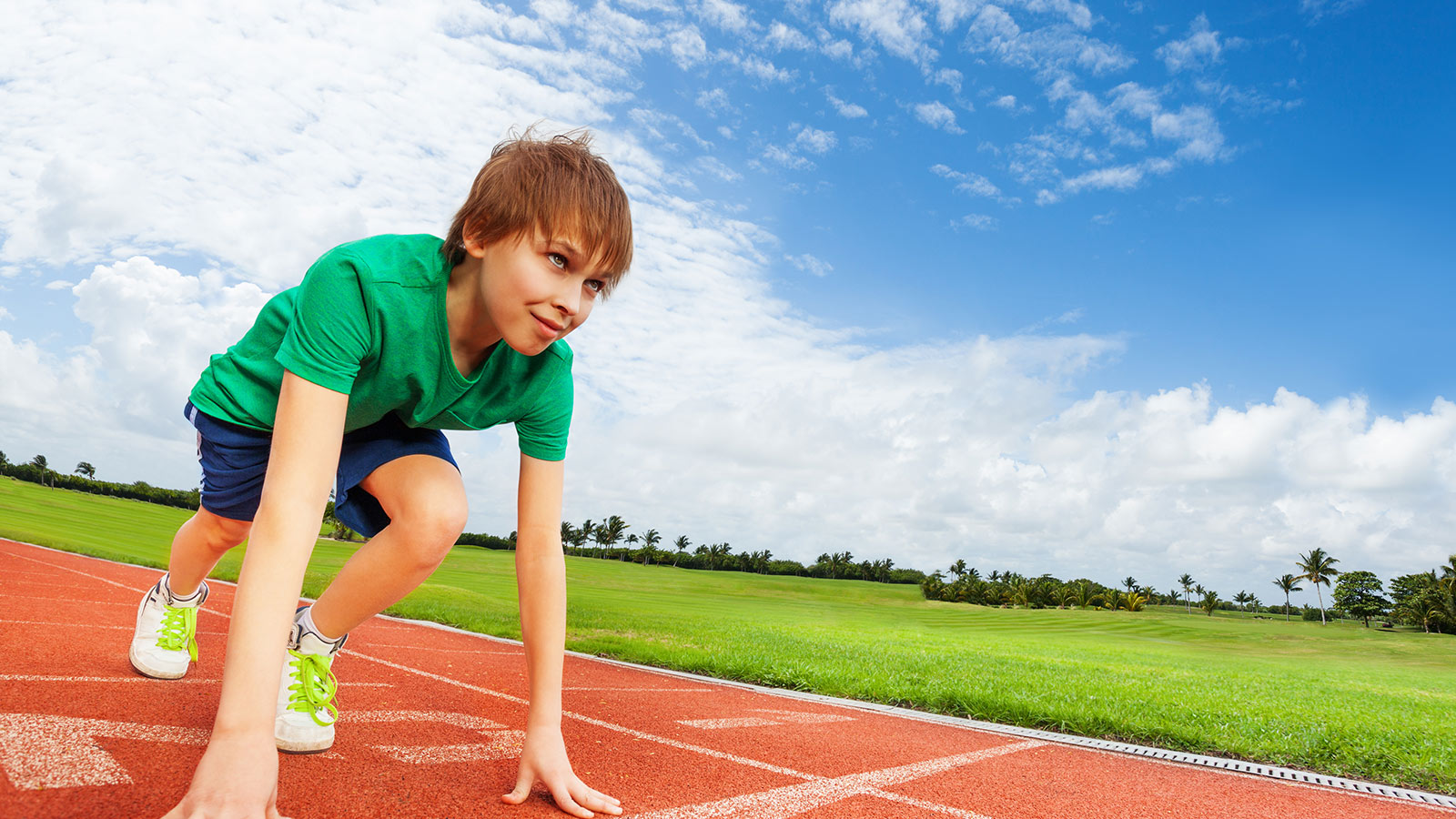 Boy in green t-shirt starting on the athletics track