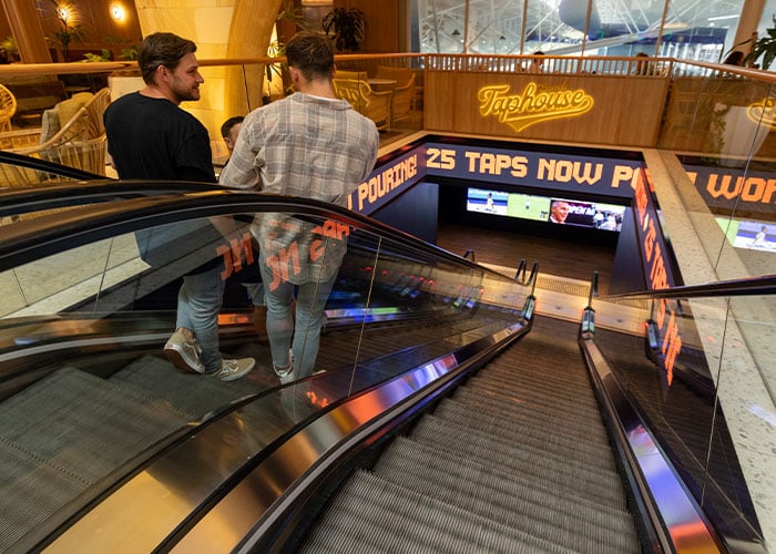 Group of men going down the escalator to Legends Taphouse at Mingara