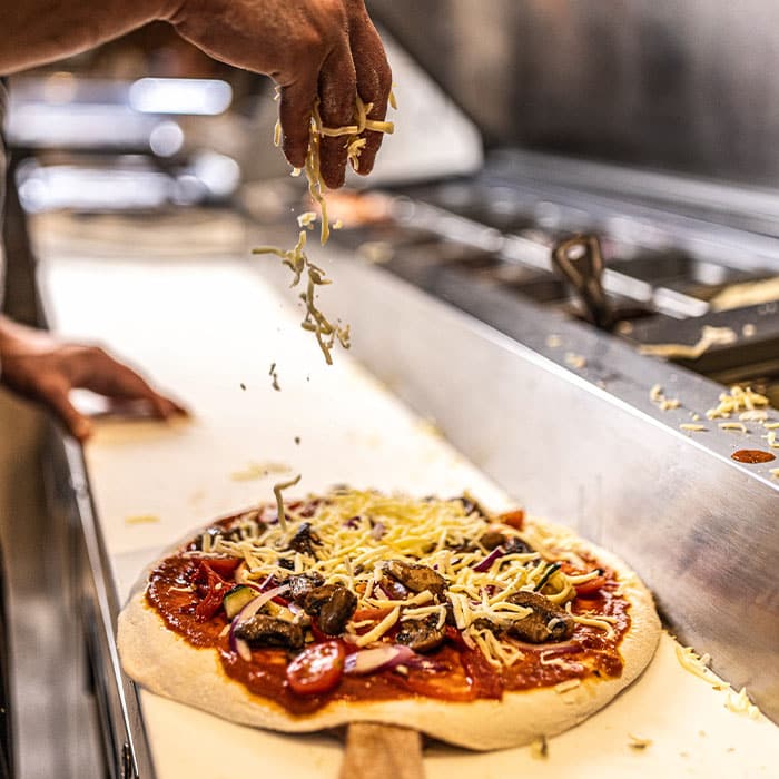 Chef at Hadley's, Mingara topping pizza with cheese